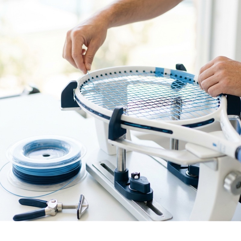 Racquet being restrung on a stringing machine